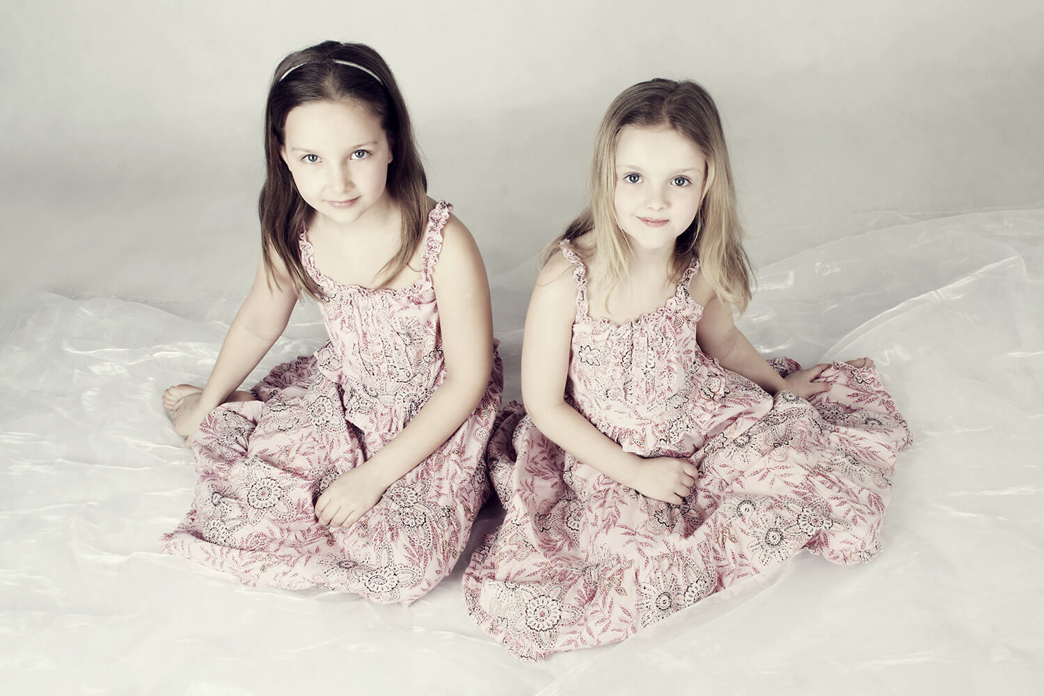 rodinná fotografie dvou sester v květovaných šatech na světlém pozadí