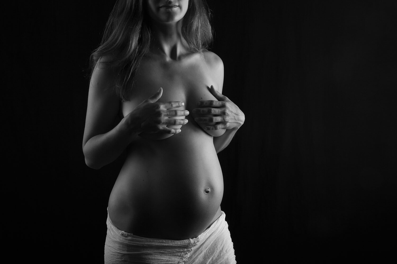black and white maternity photo with a white skirt on a dark background