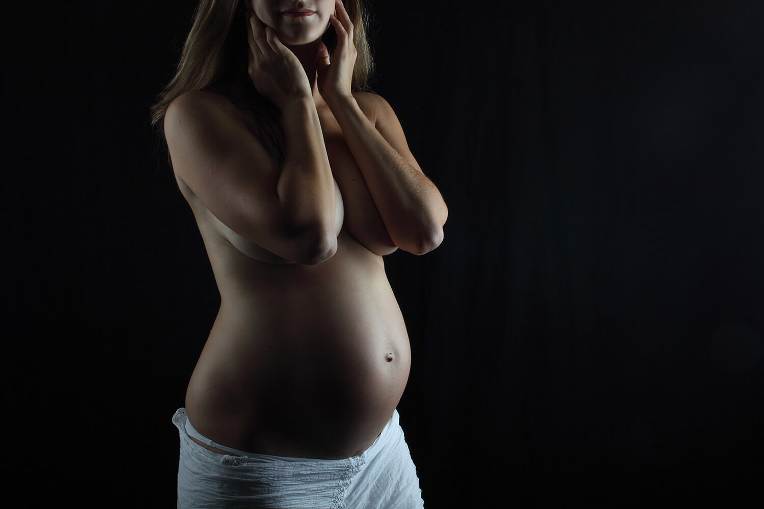 maternity photo with a white skirt on a dark background