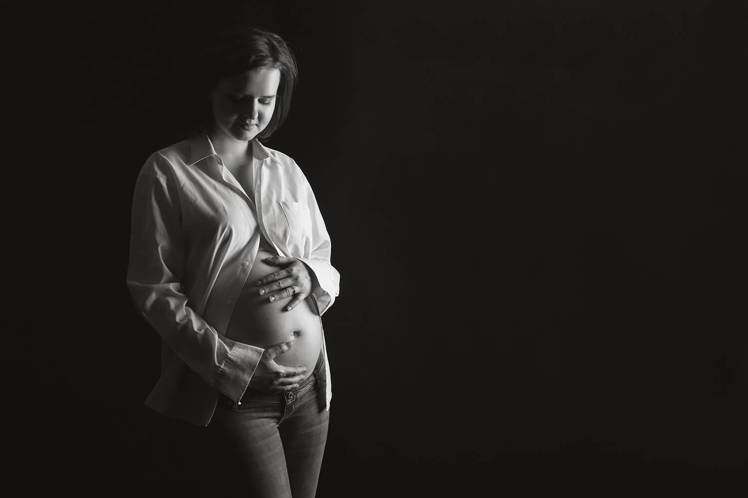 černobílá těhotenská fotografie ženy na černém pozadí