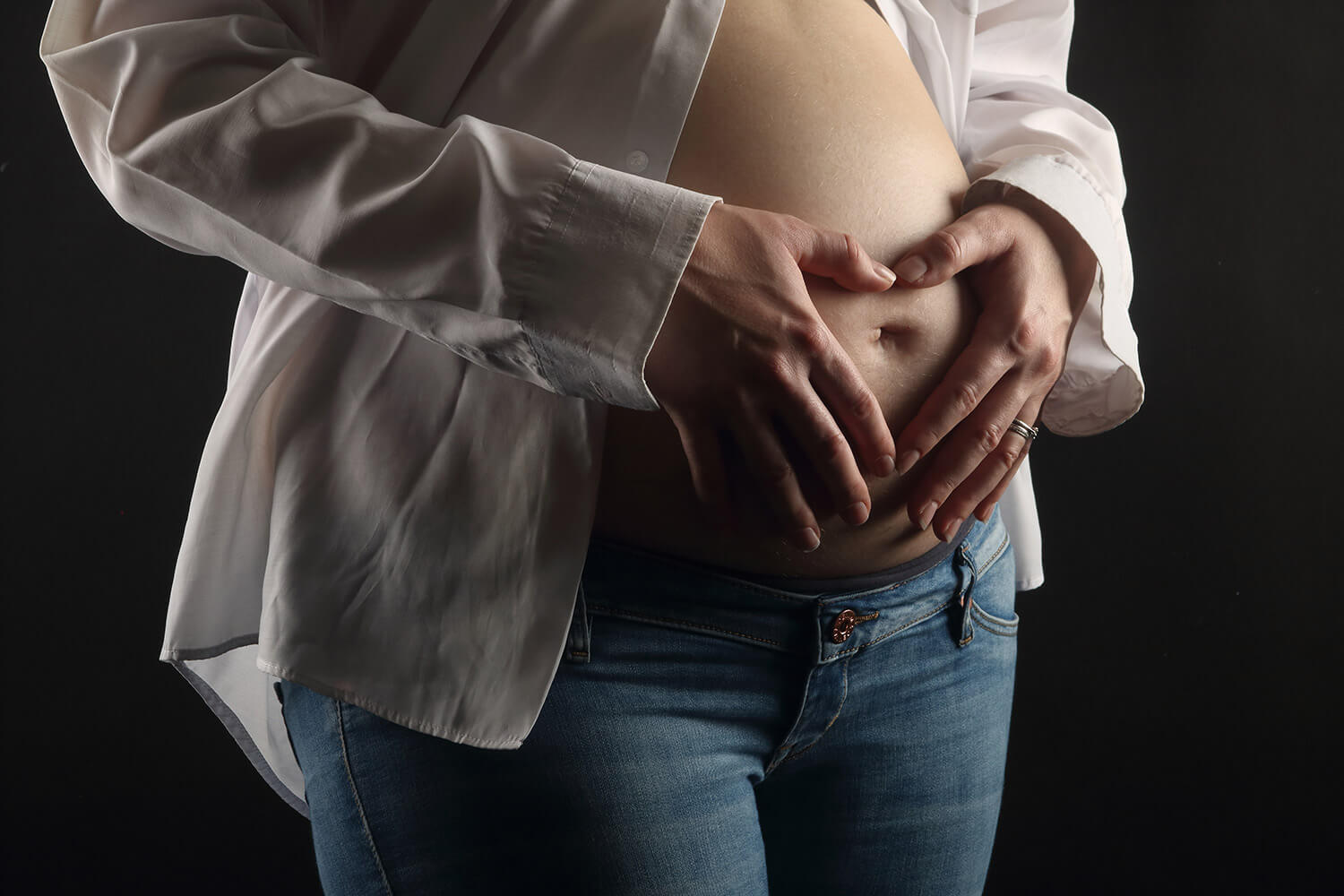těhotenská fotografie s rukami tvořícími srdíčko na bříšku