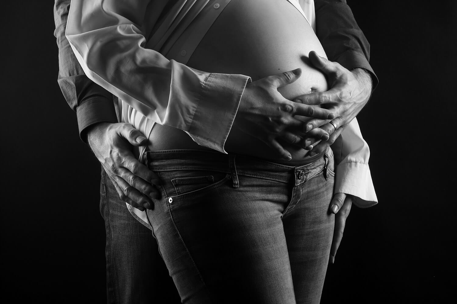 black and white maternity photo of a couple with their hands on the belly