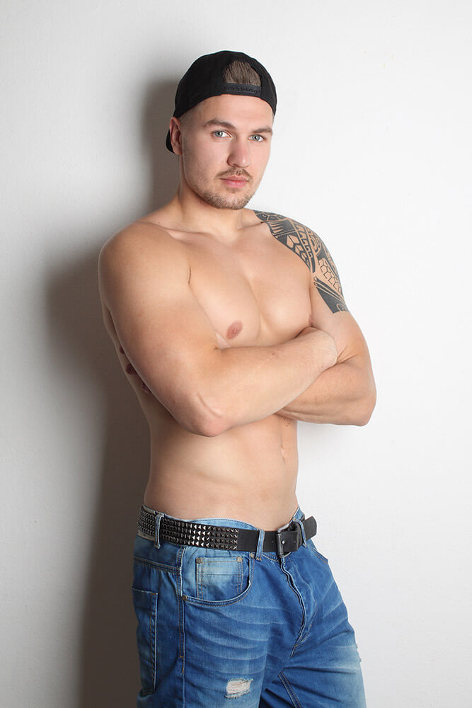 shirtless male portrait with a baseball hat on light background