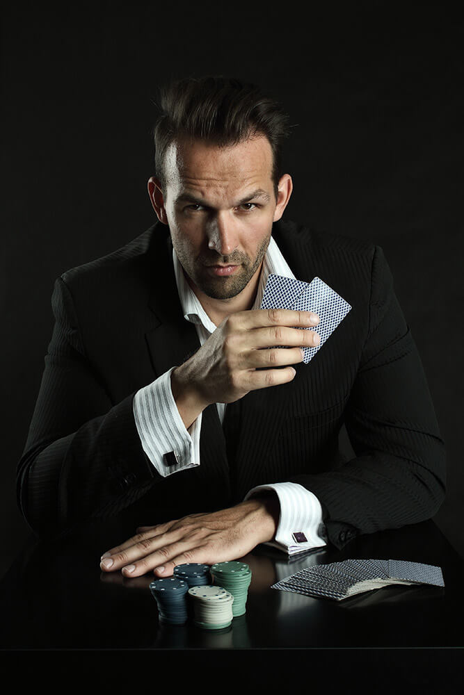 mužský portrét v obleku, s kartami a žetony na černém pozadí