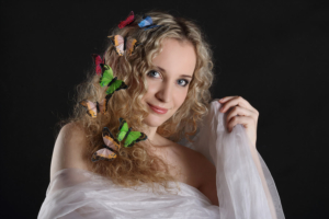 portrait of a woman with butterflies in her hair on a dark background