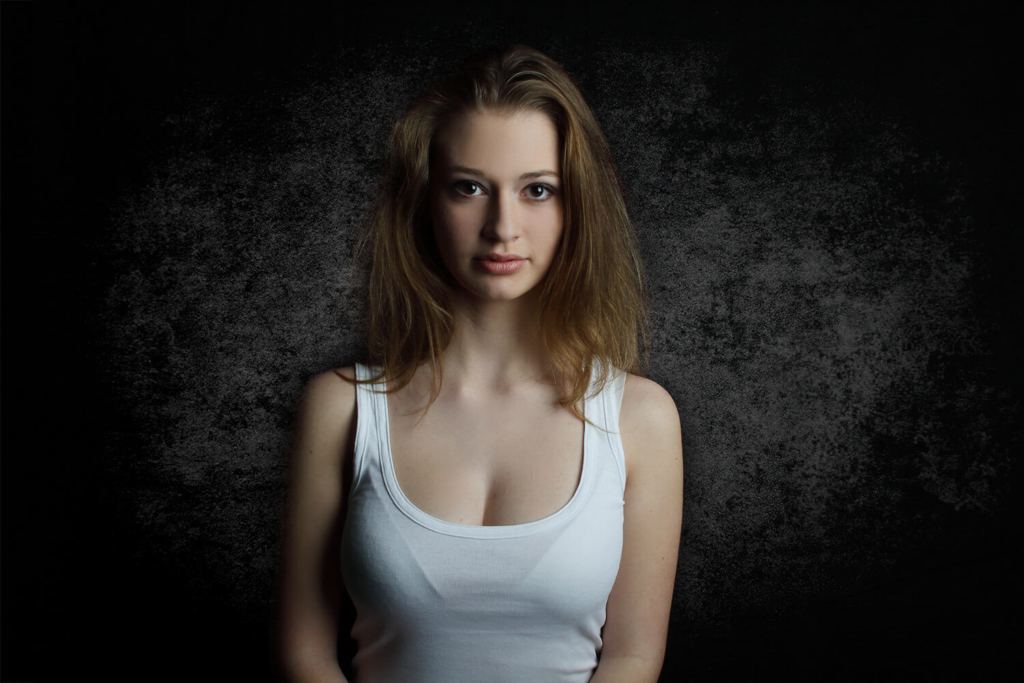 portrait of a woman in a white tank top on a dark textured background