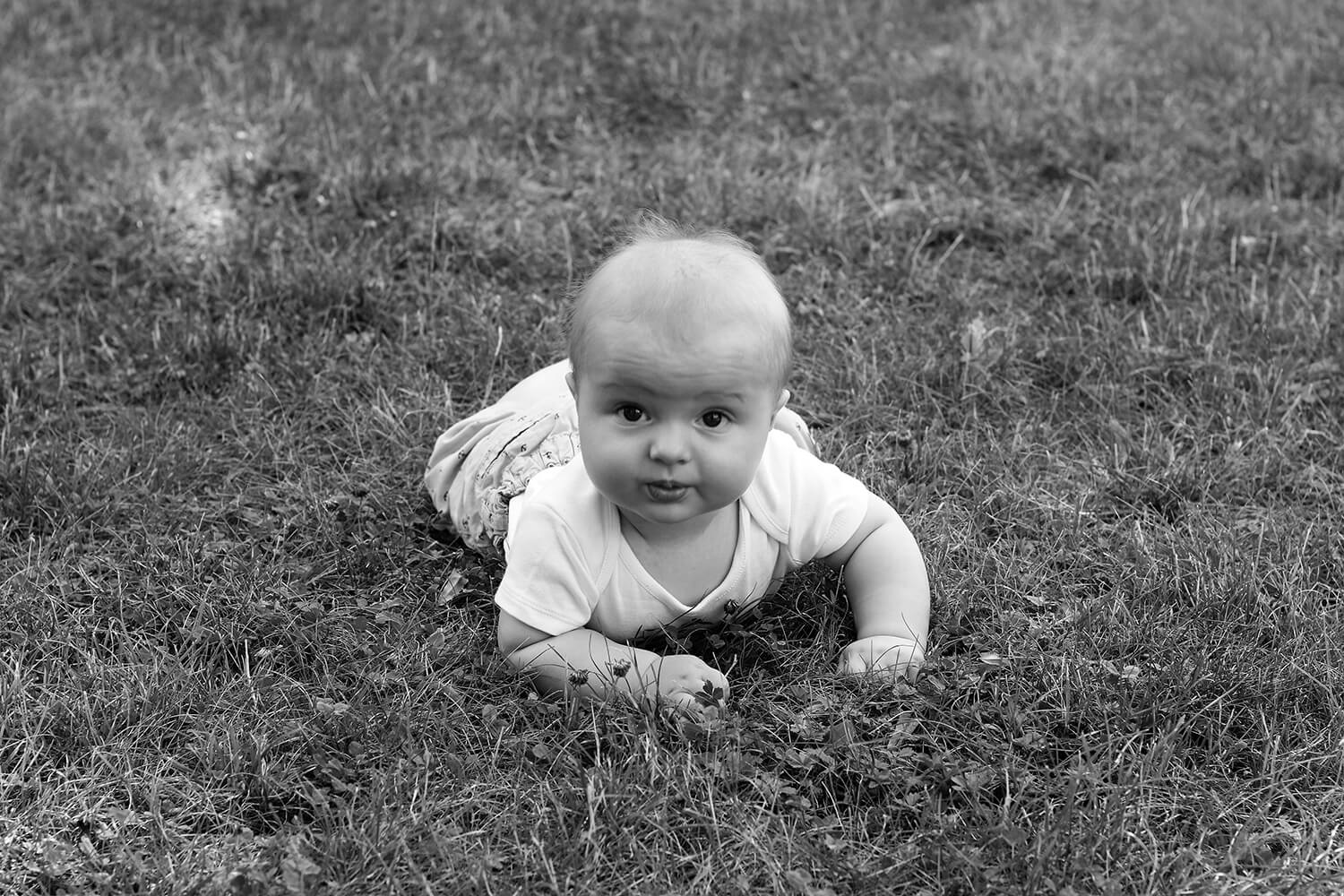 černobílá rodinná fotografie batolete na trávě
