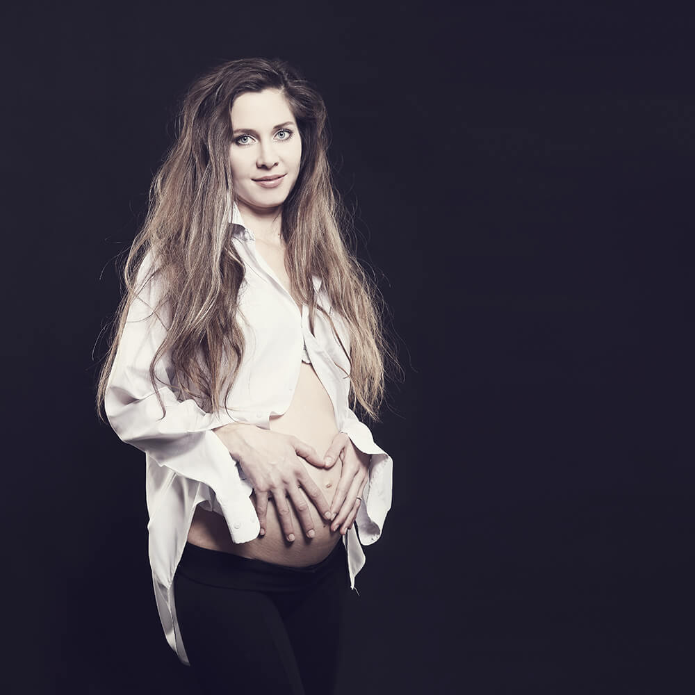 maternity photo in white shirt on a dark background
