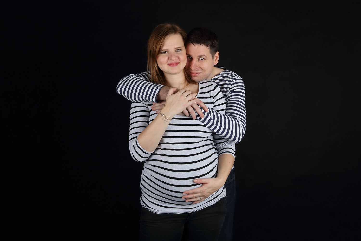 párová těhotenská fotografie v pruhovaných trikách na tmavém pozadí