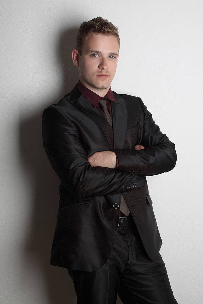 mužský business portrét v černém obleku s kravatou na světlém pozadí