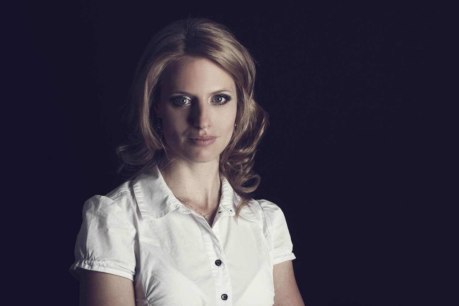 ženský business portrét v bílé košili na tmavém pozadí
