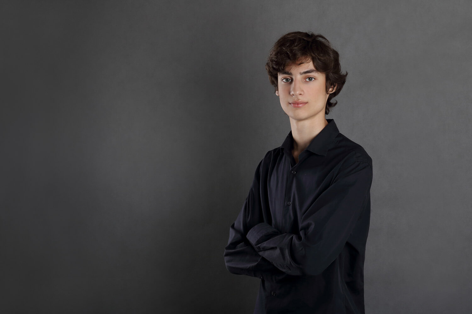 umělecký portrét mladého herce v černé košily na šedém pozadí
