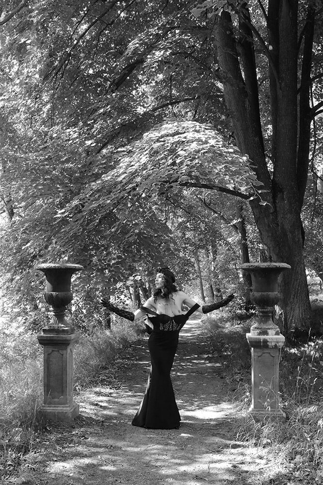 Boudoir černobílá fotografie ženy v černých šatech v přírodě