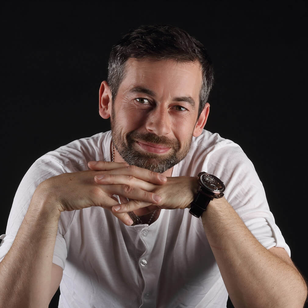 portrét usmívajícího se muže se založenýma ruka pod bradou