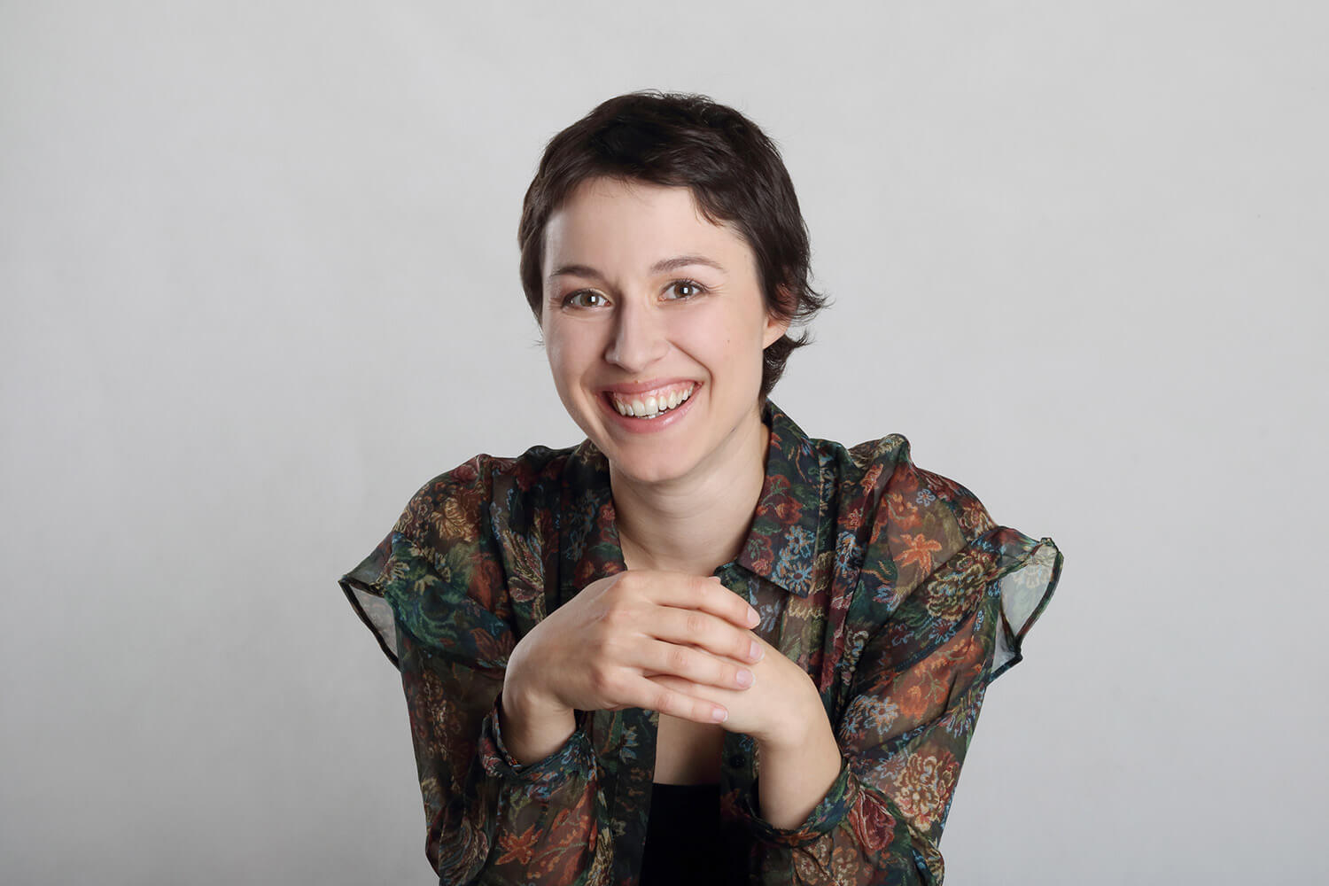 Natural actor headshot of a smiling woman against a light background.