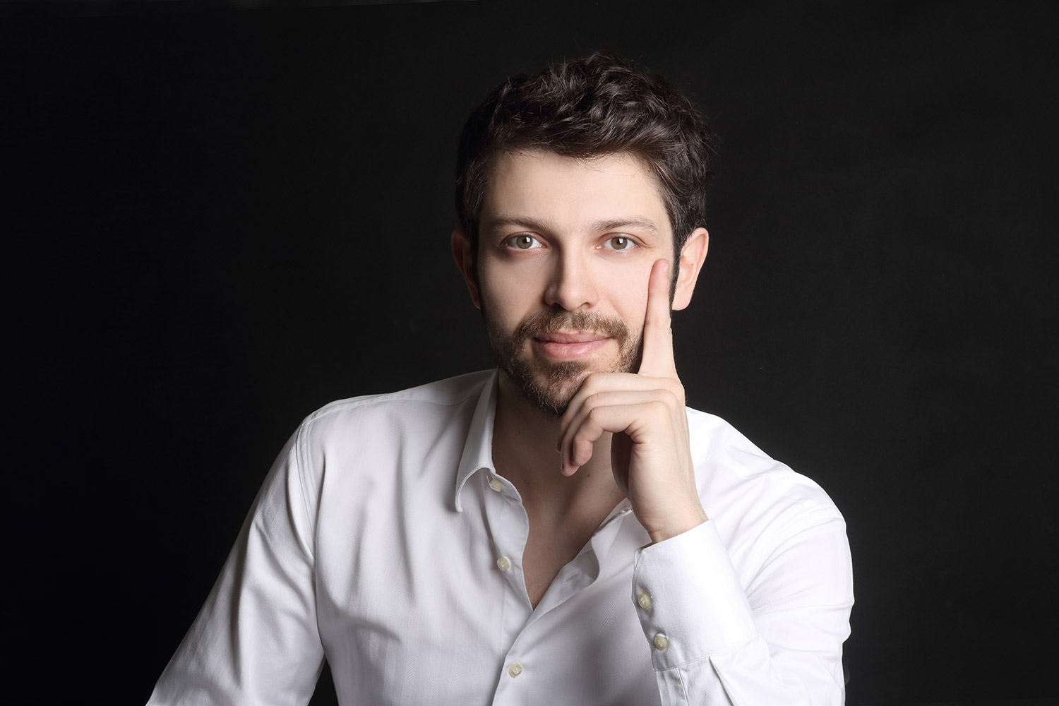 Studio business portrait of a man in a white shirt against a dark background.