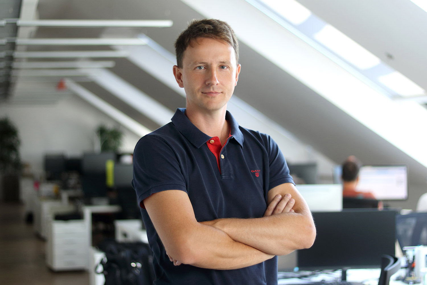 Business portrait of a man standing with arms crossed in a modern office.