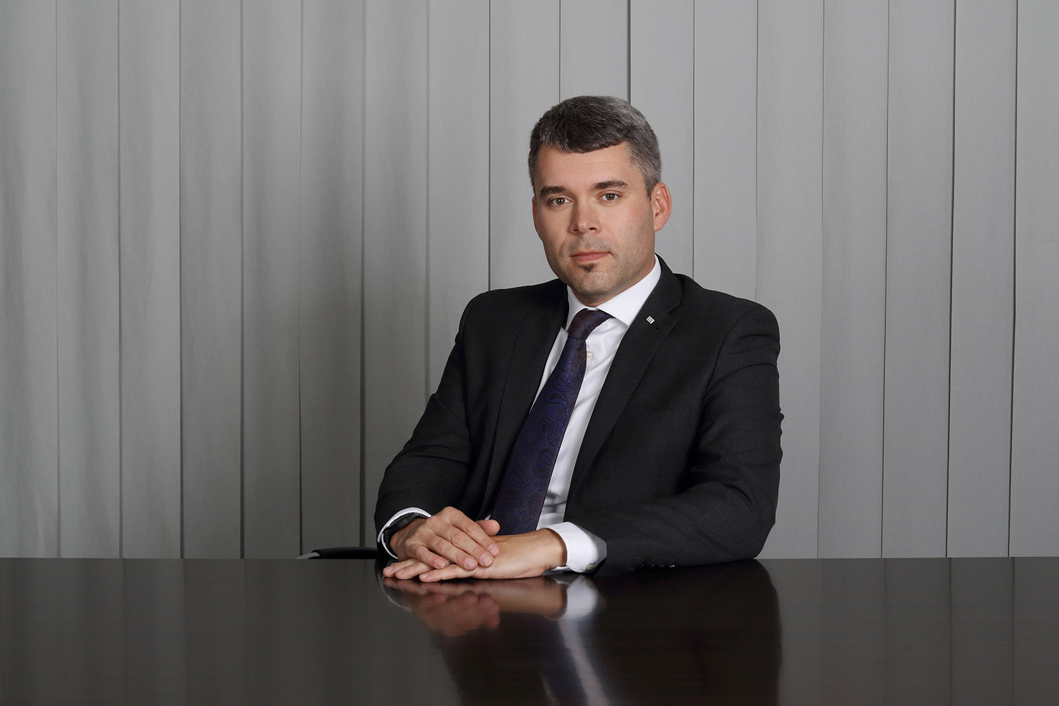Executive business portrait of a CEO in a suit at a conference table.