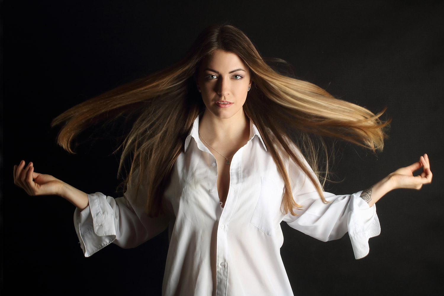 Casting portrait of a woman in a white shirt with hair in motion.