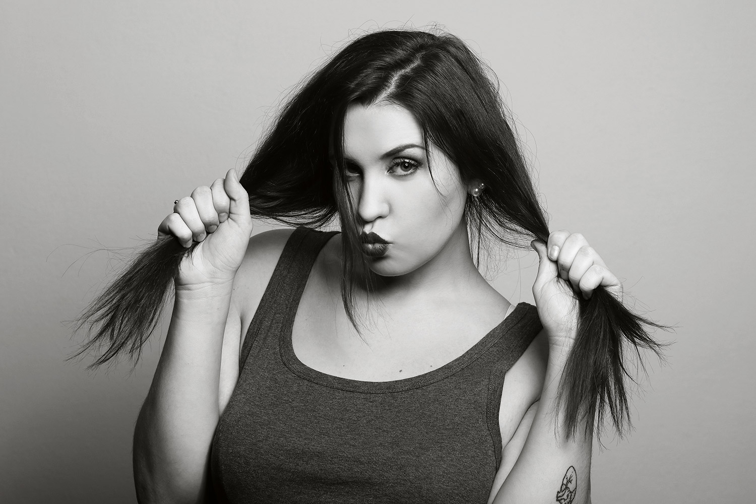 Black-and-white expressive portrait of a woman holding her hair.